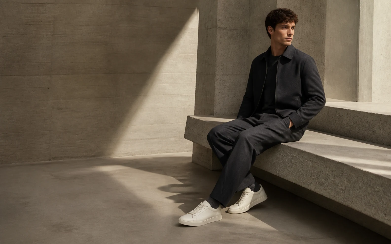 Marquant model in a concrete interior wearing off-white leather sneakers